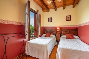 Una habitación con dos camas, techo de madera, una ventana y una puerta.