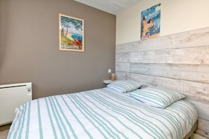 Une chambre à coucher avec un lit, une tête de lit en bois, un radiateur et deux affiches accrochées au mur.