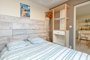 Une chambre à coucher avec une tête de lit en bois, un lit avec une literie à rayures, une armoire et une affiche accrochée au mur.