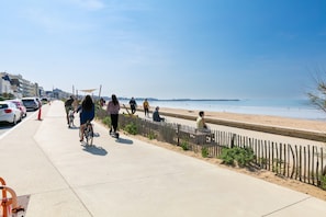 Une promenade en bord de mer avec une plage de sable, une clôture en bois et un ciel dégagé.
