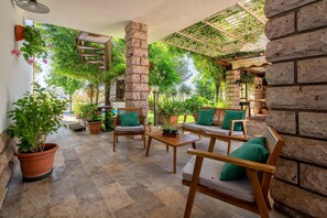 Eine Terrasse im Freien mit Holzmöbeln, Topfpflanzen und einer Ziegelwand.