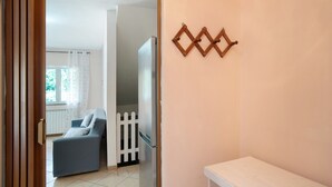 A room with a white door, a blue sofa, a white table, and a wall-mounted decorative item. - Villa 'Il Frutteto 49' with Private Terrace and Wi-Fi (Ortovero)