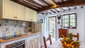 Cozinha com painel de azulejos, armários de madeira, micro-ondas e uma cesta de frutas na mesa.