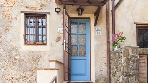 Um edifício com porta azul, janela com grades de metal e parede de pedra.