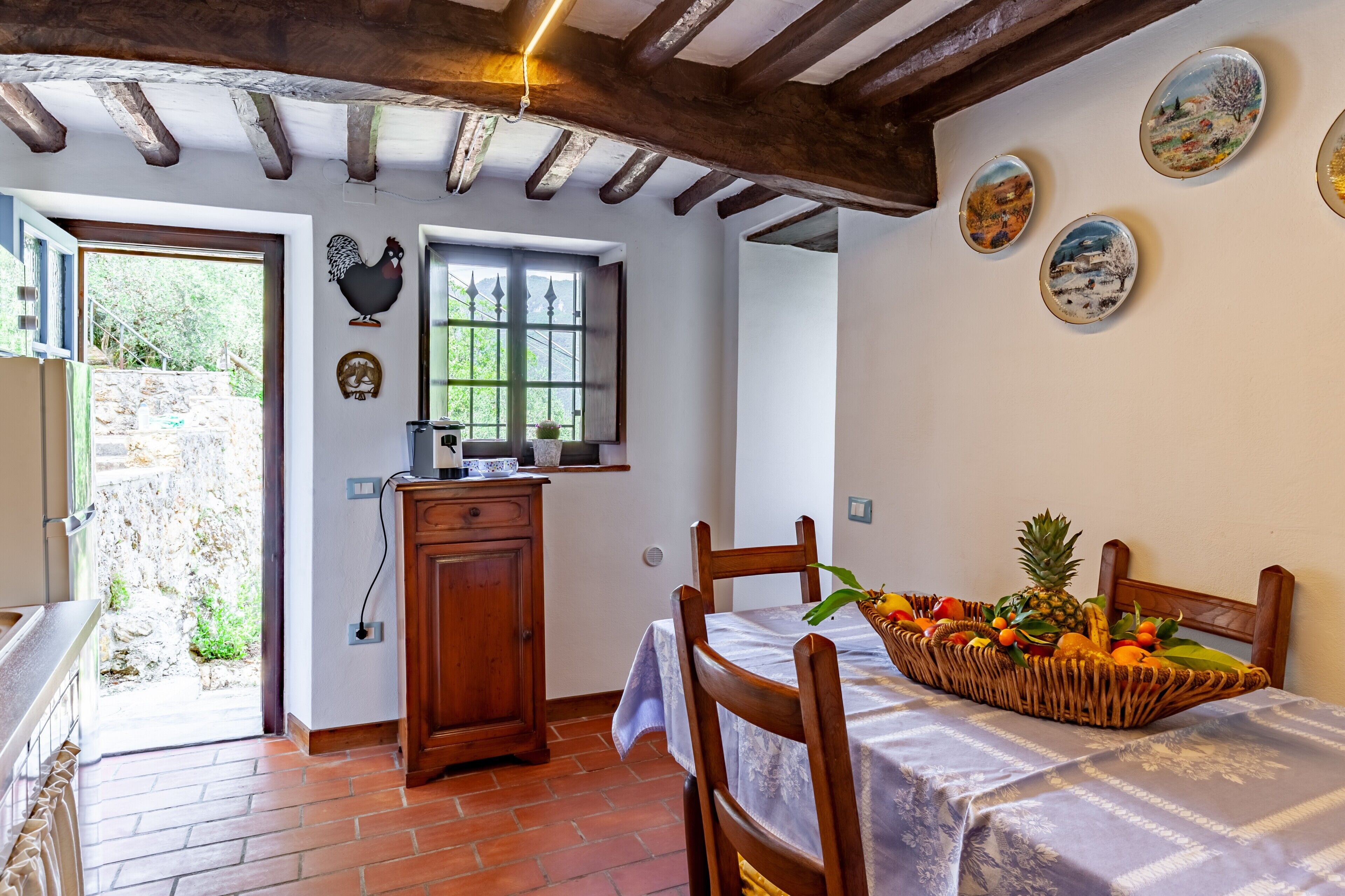 Una cocina rústica con un armario de madera, una ventana con vistas y un comedor con cesta de frutas.