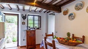 Uma cozinha rústica com armário de madeira, janela com vista e área de refeições com cesta de frutas.