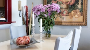 Una mesa de comedor con un jarrón de flores moradas, una vela y un plato decorativo.