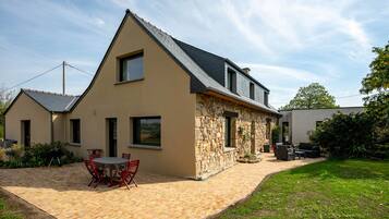 A house with a stone exterior, a tiled patio, and a small garden area.