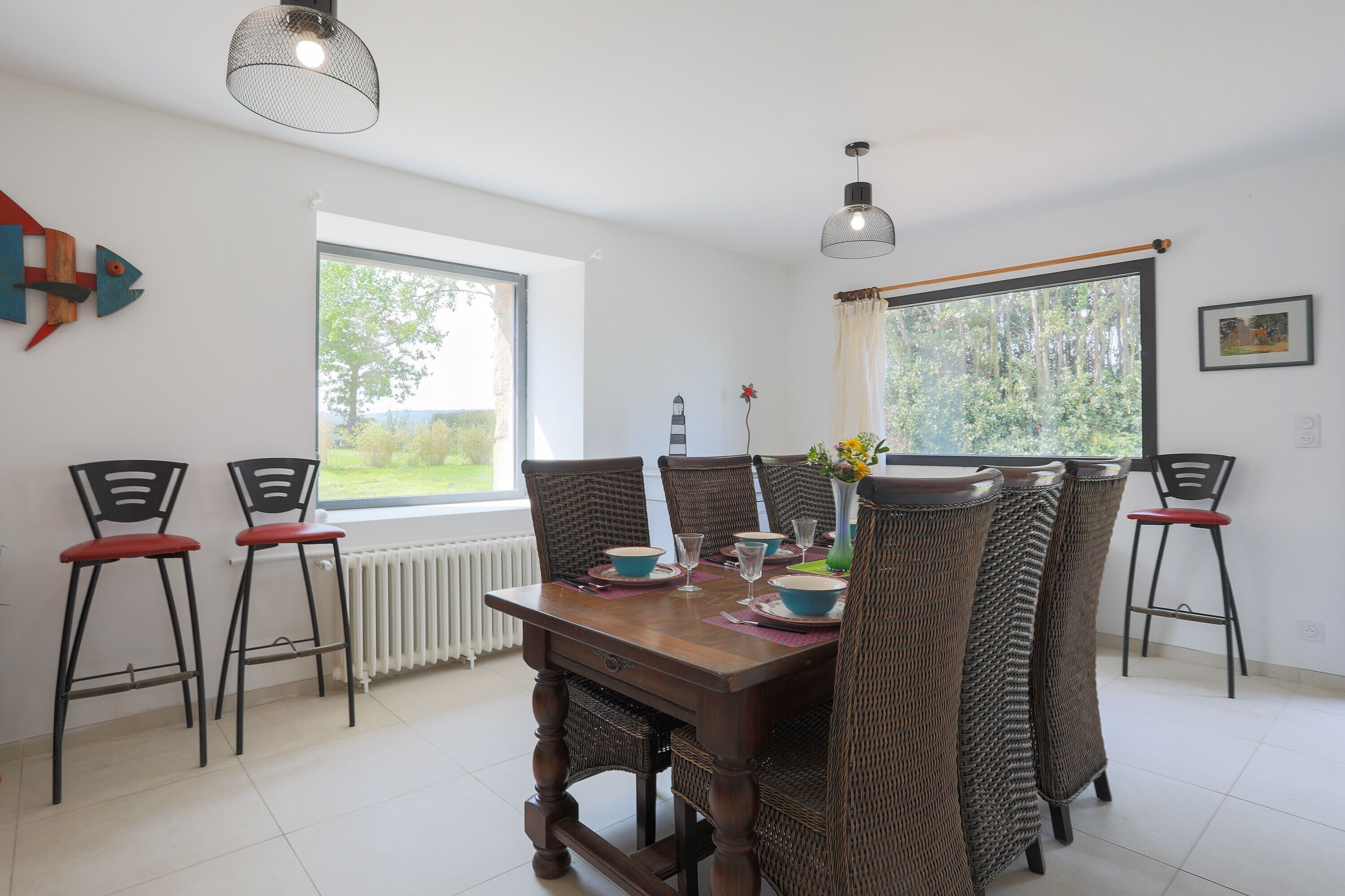 A dining area with a wooden table, four chairs, and two pendant lights.