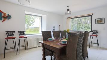A dining area with a wooden table, four chairs, and two pendant lights.