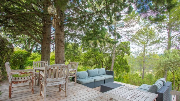 A wooden deck with outdoor furniture, including a table, chairs, and a sofa.