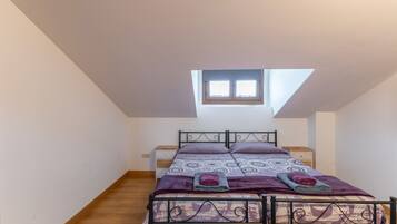 Une chambre avec un plafond en pente, un puits de lumière, un lit avec une literie à motifs et une table de chevet.