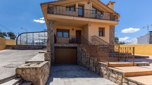 Una casa a due piani con facciata in pietra, un garage e un balcone.