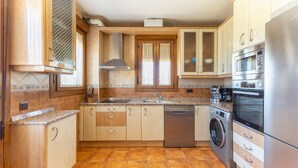 Una cucina con mobili in legno, lavastoviglie, lavatrice e forno integrato.