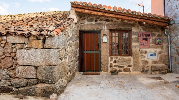 Il s’agit d’un bâtiment en pierre, doté d’un toit en tuiles, d’une porte en bois et d’une enseigne indiquant qu’il s’agit d’une maison de campagne.