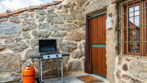 Un bâtiment en pierre avec un barbecue et une bouteille de propane à l’extérieur.