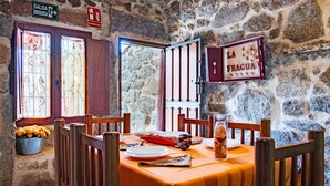 Une pièce aux murs de pierre, avec une table dressée pour le repas, un seau rempli de fleurs et un panneau indiquant la sortie de secours.
