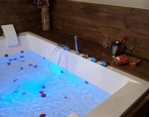 A bathtub with water jets, a wooden wall, and a small shelf with items. - Holiday Home 'La Cantina' with Mountain Views (Villar de Corneja)