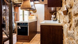 Eine Küche mit Steinwand, Holzschränken, einem Einbauofen und einer Kaffeemaschine.