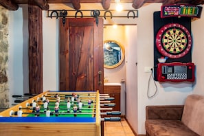 Um quarto com mesa de pebolim, dardos e placar.