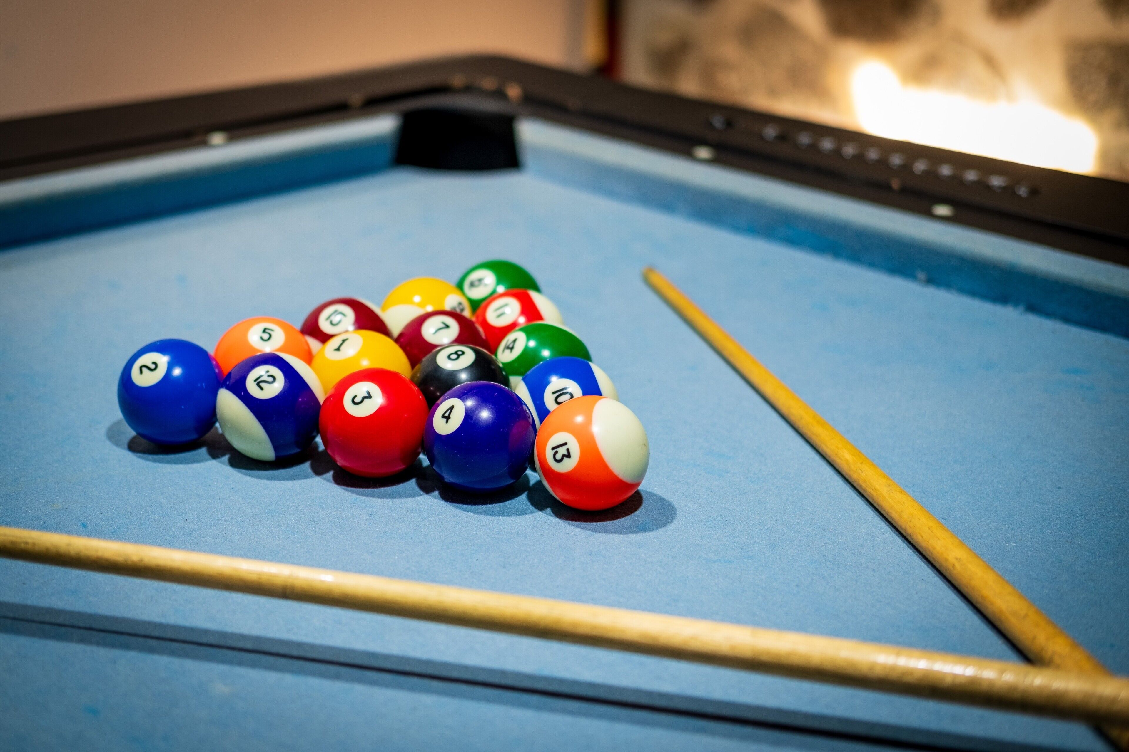 Une table de billard avec des billes numérotées et des queues de billard.