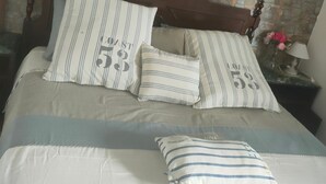 A bed with striped pillows and a stone wall behind it. - Holiday Home 'Casetta Esmeralda' with Sea View, Private Terrace and Wi-Fi (Tortora Marina)