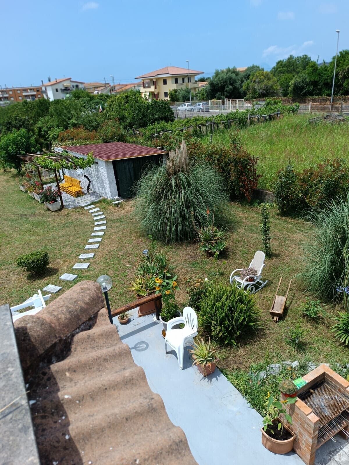 Un giardino pensile con zona barbecue, posti a sedere all'aperto e diverse piante.