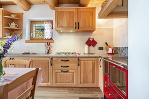 A kitchen with wooden cabinets, a stove, and a red oven.