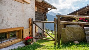 Una cabaña rústica de madera con una ventana, un banco de madera y una gran roca.