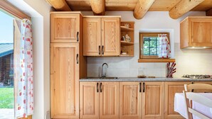 Una cocina con armarios de madera, encimera de granito, un lavamanos y una ventana con vista a la vegetación.