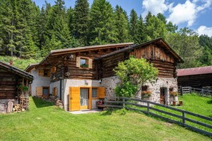 Une cabane rustique en rondins de bois, avec un mur en pierre, des portes en bois et une clôture en bois.