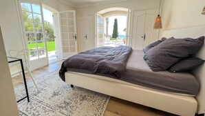 A bedroom with a bed, a chair, a table, and a view of the outdoors. - Villa 'Le Gabian' with Sea View, Wi-Fi and Air Conditioning (Sainte Maxime)