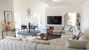 A modern living room with a sectional sofa, a dining table with chairs, a TV, and a bookshelf. - Villa 'Le Gabian' with Sea View, Wi-Fi and Air Conditioning (Sainte Maxime)