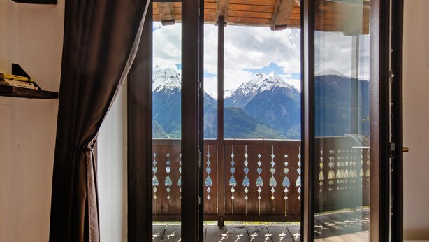 Une pièce avec vue sur des montagnes enneigées, visible à travers une porte vitrée.