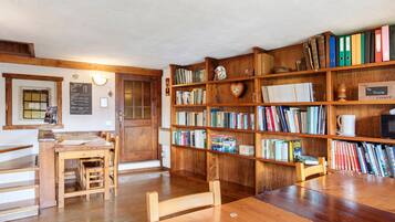 Une bibliothèque avec des étagères en bois, une table en bois et des chaises.