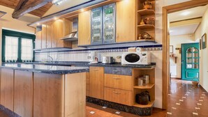 Una cocina con armarios de madera, encimera de granito, microondas y cafetera.