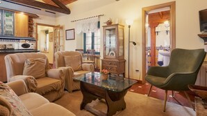 Una sala de estar acogedora con una mesa de centro de vidrio, un sofá, una silla y un aparador con puertas de cristal.