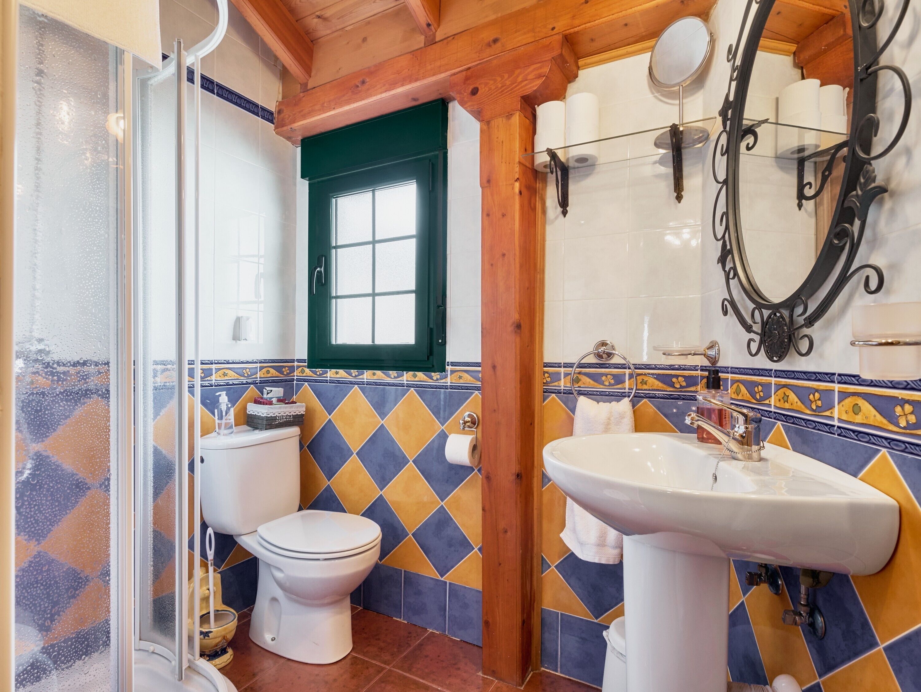 A bathroom with a shower, toilet, sink, and decorative tiles.