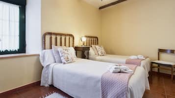 A bedroom with two beds, a small table, and a chair.