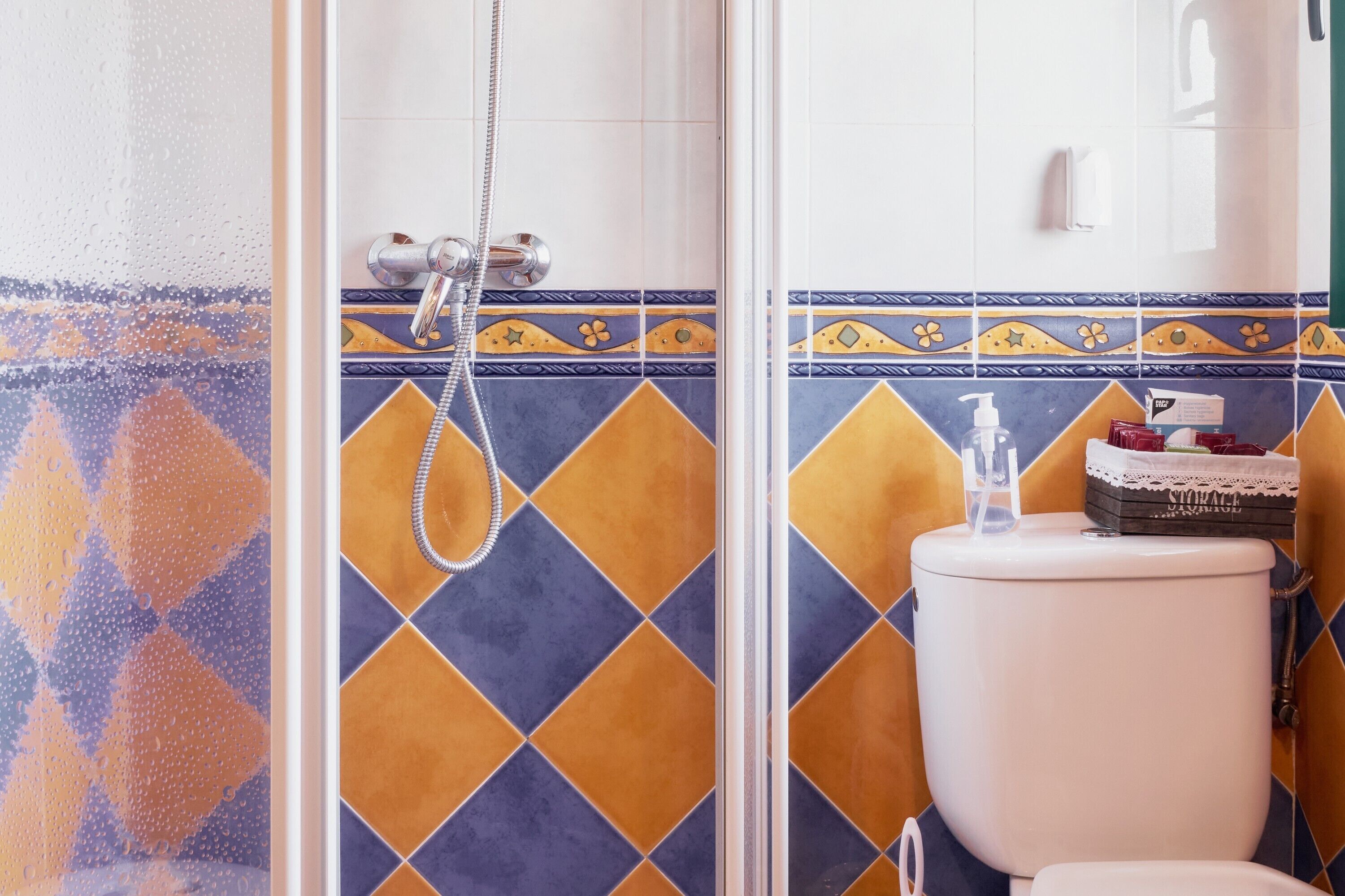 A bathroom with a shower, toilet, and a storage box on the wall.
