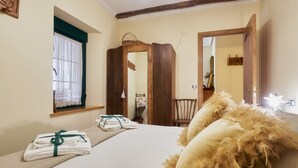 Un dormitorio con una cama, una ventana con cortinas, una puerta de madera y un espejo.
