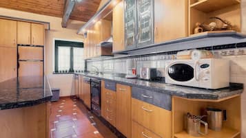 Una cucina con mobili in legno, un forno a microonde, un tostapane e una finestra con tende.