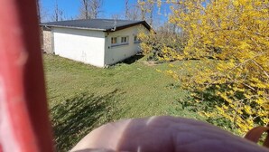 A small white building with a dark roof, surrounded by grass and yellow foliage. - Cottage 'Le Paradis De Marie' with Private Terrace and Private Garden (Treignac)