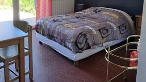 A bedroom with a bed, a desk, a chair, a window with curtains, and a view of greenery outside. - Cottage 'Le Paradis De Marie' with Private Terrace and Private Garden (Treignac)