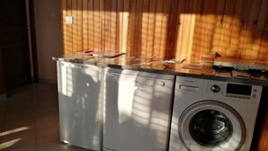 Pesutila, jossa on kaksi pesukonetta, laatoitettu lattia ja puupanelointi seinissä.