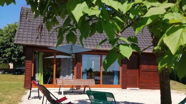 Talo, jossa on patio, ja patiolla on penkki ja tuoleja sekä varjoa antava puu.