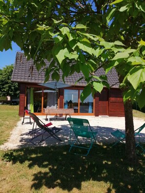 A house with a patio area, including a bench and chairs, and a tree providing shade. - Chalet 'Mon Petit Coin De Paradis' with Private Terrace and Private Garden (Darazac)