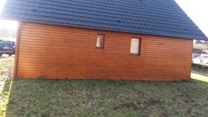 Pieni puinen rakennus, jossa on kalteva katto, pieni ikkuna ja edessä ruohikkoalue.
