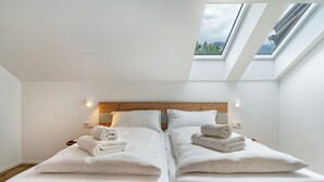 A bedroom with two beds, skylights, and a wooden headboard. - Apartment '1' with Mountain View, Wi-Fi and Air Conditioning (Auer)