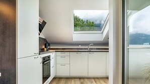 A modern kitchen with white cabinets, a built-in oven, a window with a view of greenery, and a skylight. - Apartment '1' with Mountain View, Wi-Fi and Air Conditioning (Auer)